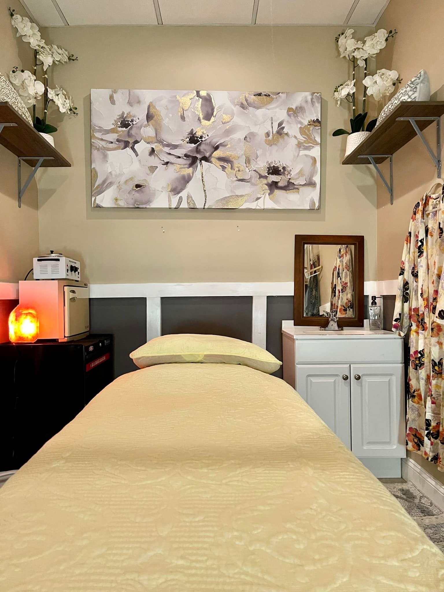 A treatment bed with orchids and a floral painting in the skin care room
